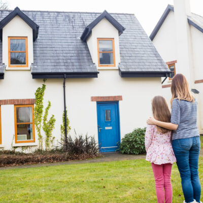 Rear view of mother and daughter standing in lawn near house