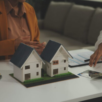 Discussion with a real estate agent, House model with agent and customer discussing for the contract to buy, get insurance or loan real estate or property.